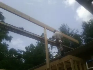 Carpenter setting a ridge beam over a new addition frame — Ice Dam Removal by Roofing Brothers in Lenox